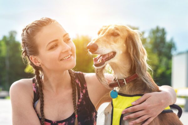 Afghan Hound Sitting With Smiling Woman Outdoors