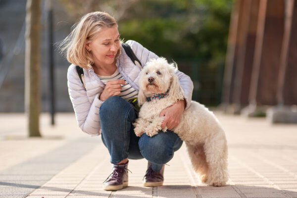 Coton De Tulear With Its Owner Crouching Beside It Outdoors