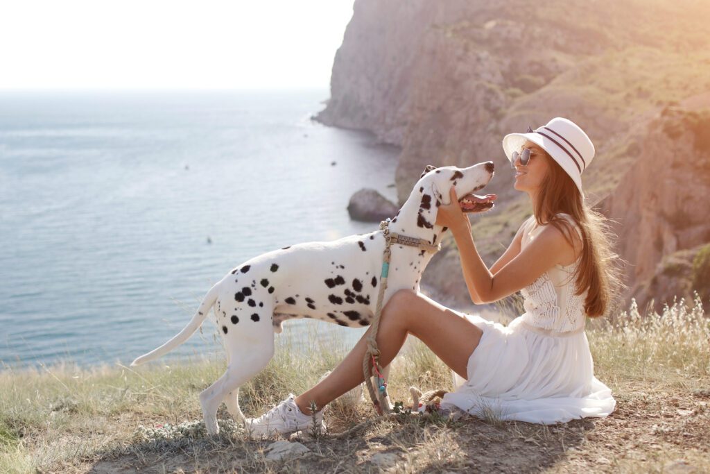 Dalmatian Standing With A Woman Near A Scenic Coastal Cliff View