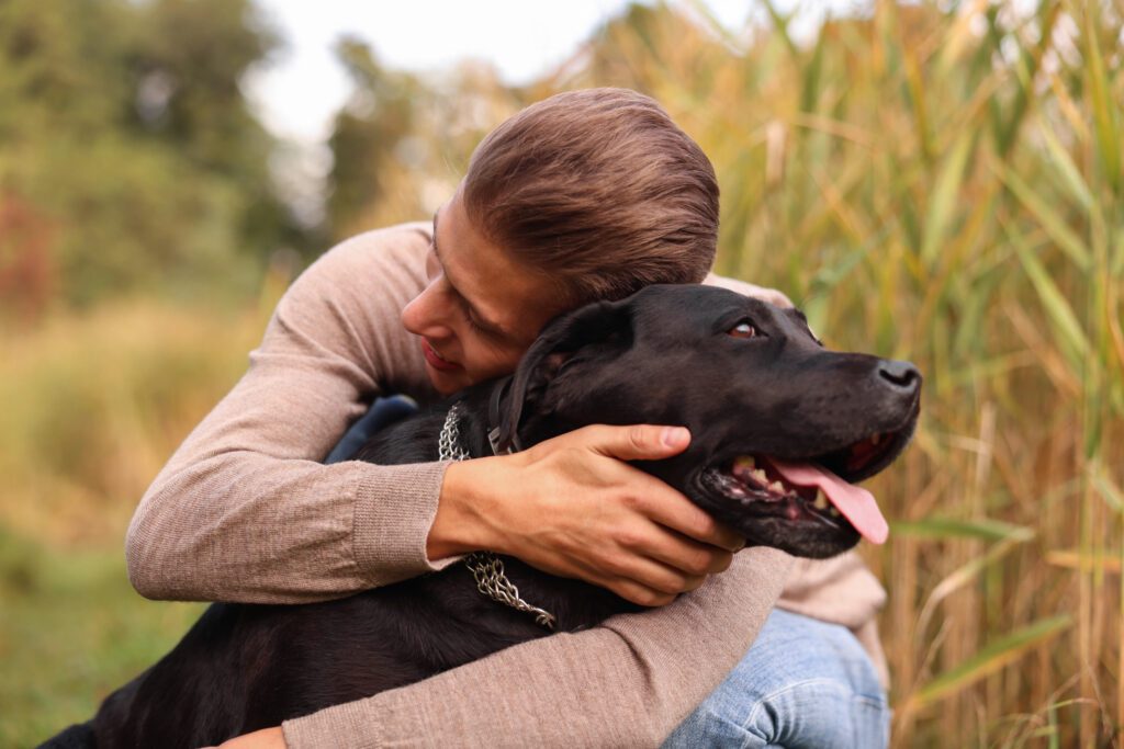 Man Hugging Black Lab Outdoors