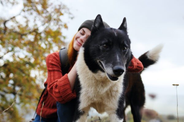 Woman Hugging A Karelia Bear Dog Outdoors
