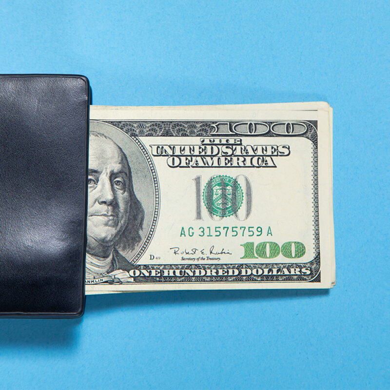 Black wallet with a dollar banknotes on the blue background.