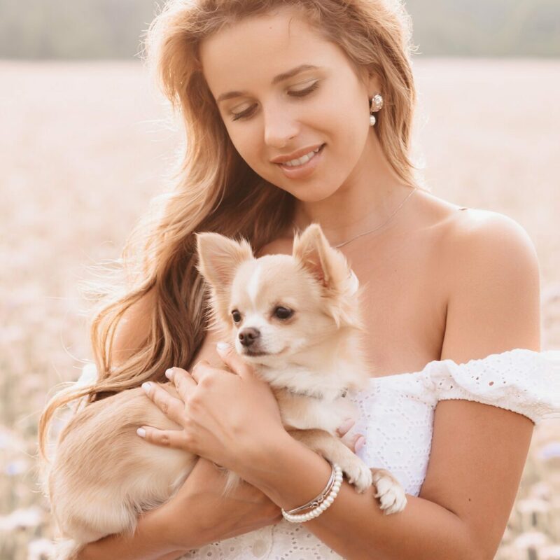 woman in white dress holding long haired chihuahua outside in texas