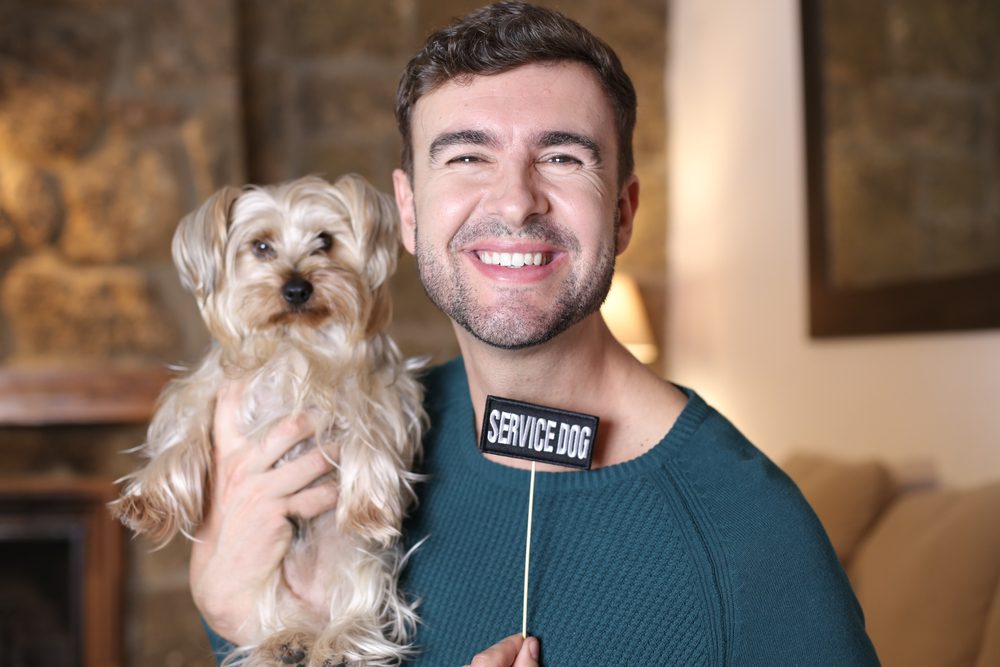 man holding service dog with sign