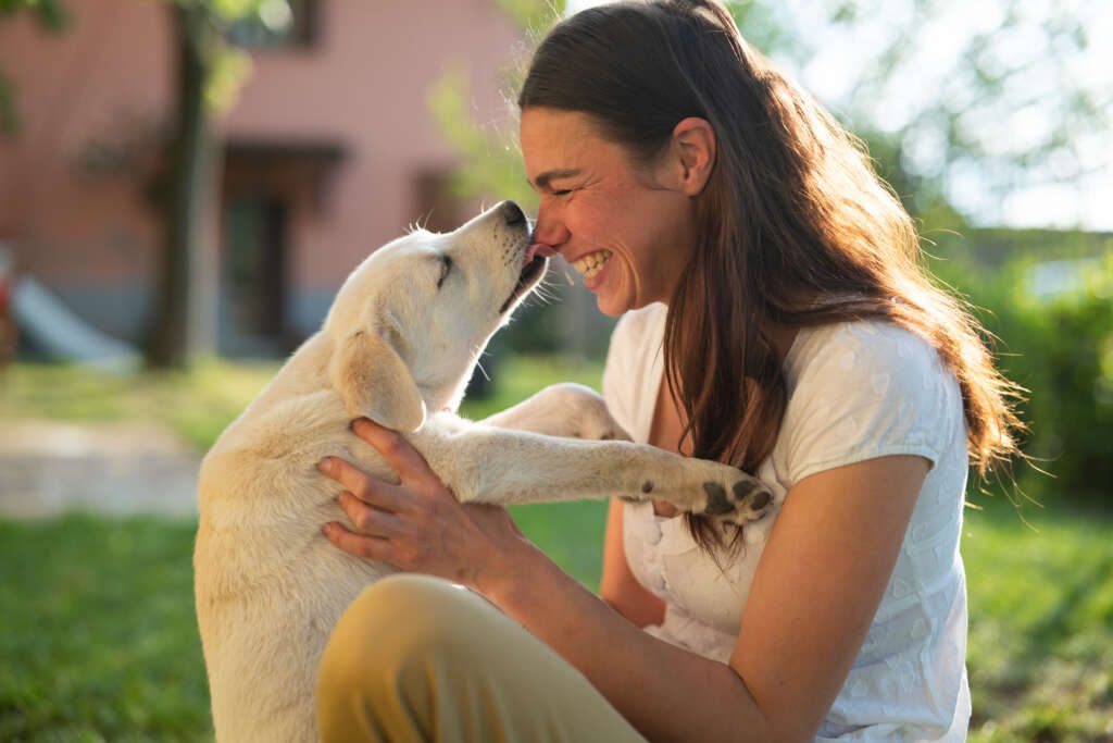 puppy licking smiling woman outside