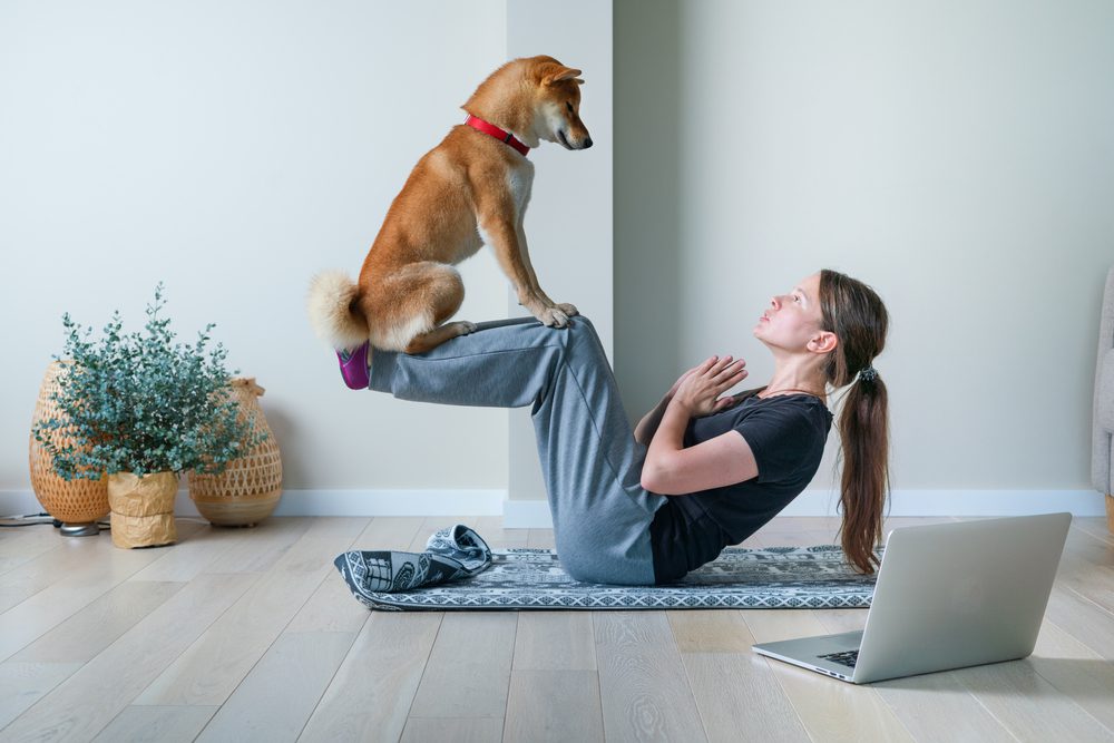 woman practicing yoga with her dog