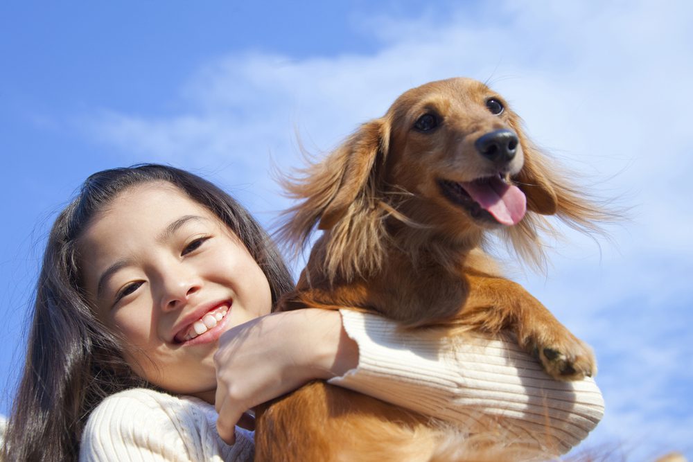 happy girl holding miniature dachshund